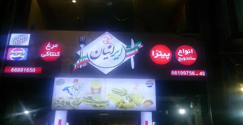 تابلوی روشن فست فود ایرانیان با منوی متنوع شامل مرغ کنتاکی، پیتزا، ساندویچ، نوشیدنی‌های پپسی و مانتین دیو و شماره تماس برای سفارش غذا.