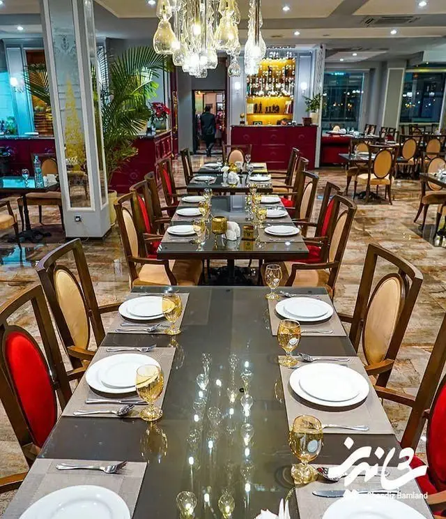 تصویری لوکس و شیک از فضای داخلی رستوران شاندیز، با میزهای چیده شده برای صرف غذا، صندلی‌های راحت و دکوراسیونی جذاب و دلنشین.