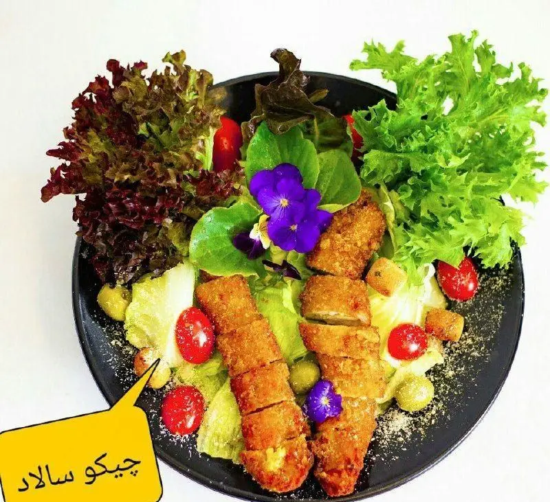 سالاد چیکو سوخاری مهدی، بشقابی پرطرفدار با تکه‌های ترد مرغ سوخاری، کاهو تازه، گوجه گیلاسی، زیتون و تزیینات گلدار.