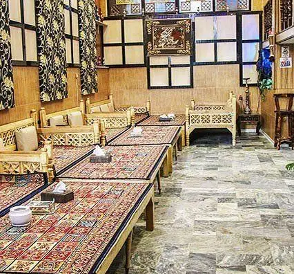 نمایی از سفره خانه طهرونیا، رستورانی با فضای سنتی ایرانی، تخت‌های چوبی و فرش‌های دستباف، ایده‌آل برای تجربه غذا و دورهمی.