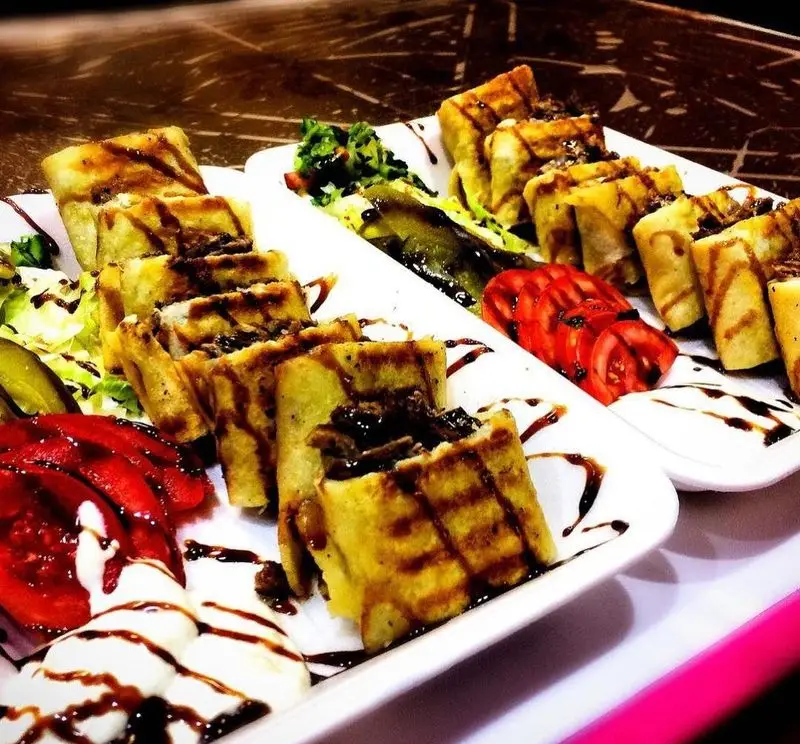 دو بشقاب کباب رولی خوشمزه و مجلسی از کباب ابوعلی، با گوشت لذیذ، سس مخصوص و دورچین تازه سبزیجات و گوجه فرنگی، مناسب رستوران کباب ابوعلی.