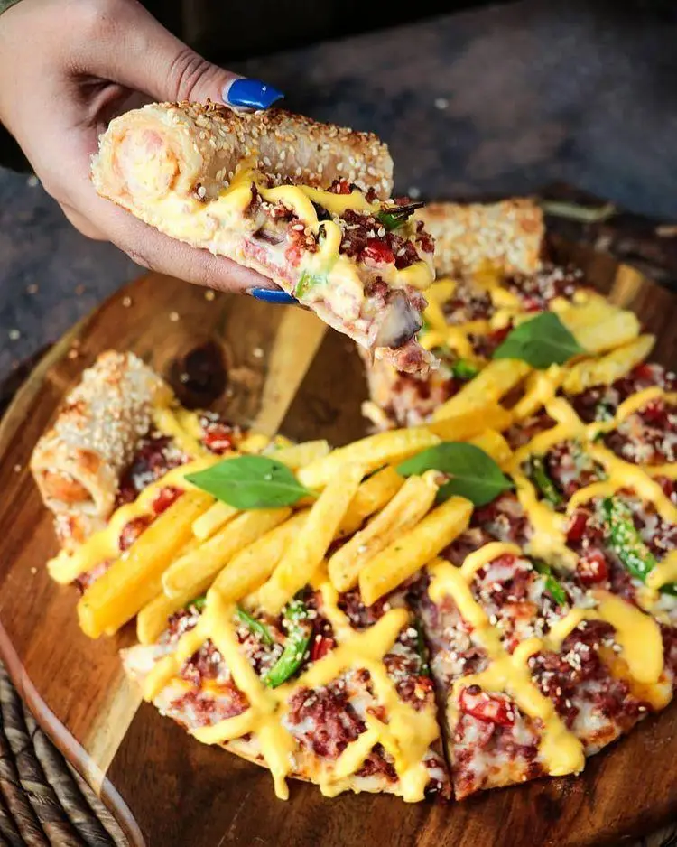 پیتزای ویژه شیلا فست فود با خمیر کنجدی پر از هات داگ، گوشت چرخ کرده، فلفل دلمه ای، سیب زمینی سرخ کرده و سس پنیر