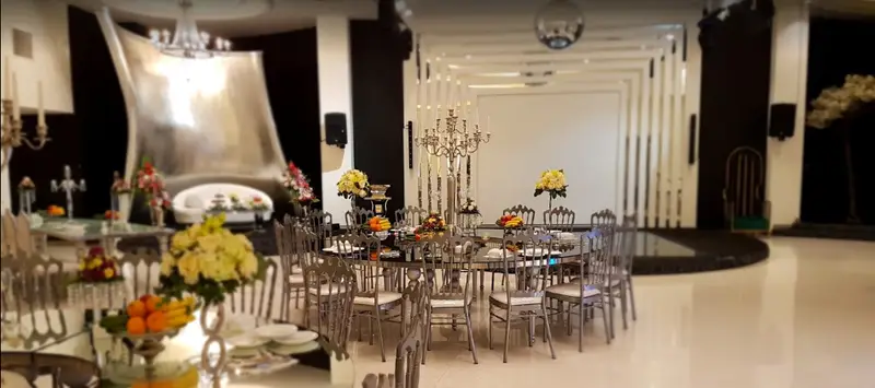 تالار پذیرایی مجلل کیان با دکوراسیون لوکس و مدرن، میز و صندلی‌های شیک نقره‌ای، گل‌آرایی و شمعدان‌های زیبا برای عروسی و جشن‌ها.