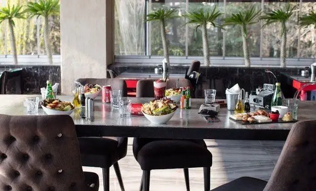 فضای دلنشین کافه راندوو با میزی پر از سالادهای تازه، نوشیدنی‌های خنک و دسرهای جذاب در محیطی روشن و مدرن.