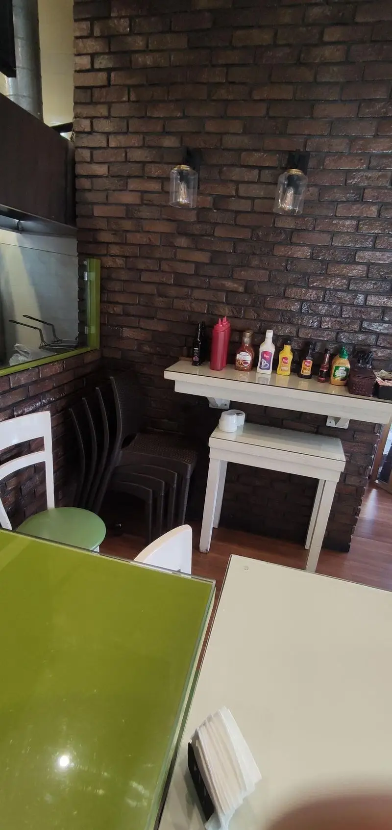 فضای داخلی دنج و دلنشین رستوران ایتالیایی سالی شعبه ستارخان با دیوار آجری جذاب، نورپردازی مدرن، قفسه سس‌های متنوع، میز و صندلی‌های شیک و ورودی آشپزخانه.