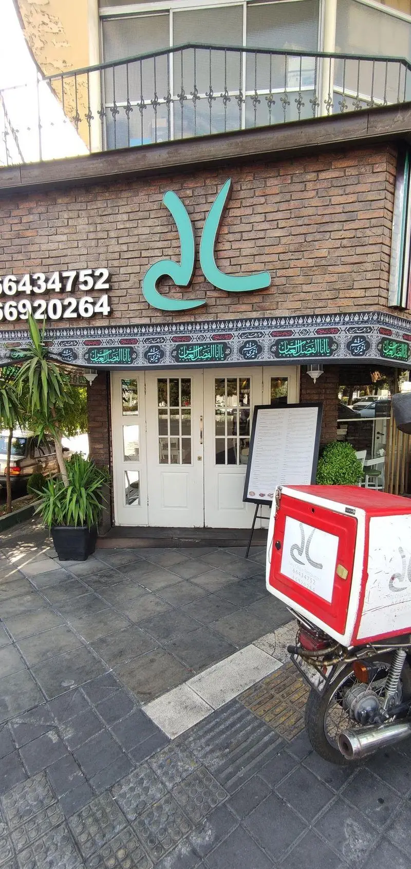 نمای بیرونی رستوران ایتالیایی سالی شعبه ستارخان: تابلوی سبز، دیوارهای آجری، شماره تلفن 66434752, 66920264 و موتور پیک آماده ارسال غذا.