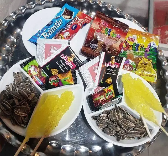 پذیرایی دلنشین کافه و سفره خانه تیام با انواع تنقلات: تخمه آفتابگردان، نبات چوبی، شکلات، آبنبات و ژله‌های رنگارنگ.