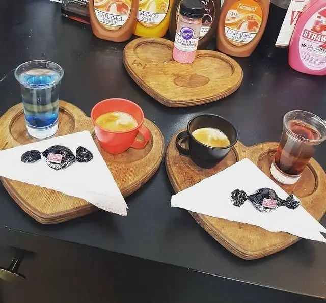 میز کافه تیام با سرو زیبا و دلنشین انواع قهوه، چای و نوشیدنی‌های فصلی همراه با شکلات‌های دست‌پیچ روی سینی‌های چوبی.