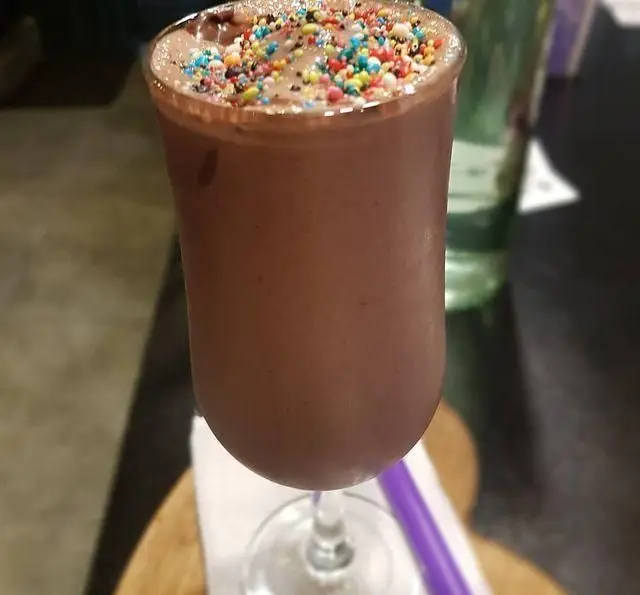 میلکشیک شکلاتی خنک و لذیذ با ترافل‌های رنگارنگ روی آن، آماده سرو در کافه و سفره خانه تیام. تجربه طعمی دلنشین.