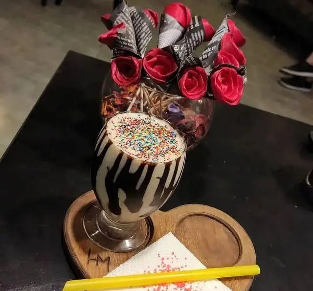 نوشیدنی شیک و خوشمزه با تزیین شکلات و اسپرینکلز رنگی در کافه تیام. تجربه طعم خاص در فضای دنج و زیبای سفره خانه تیام.