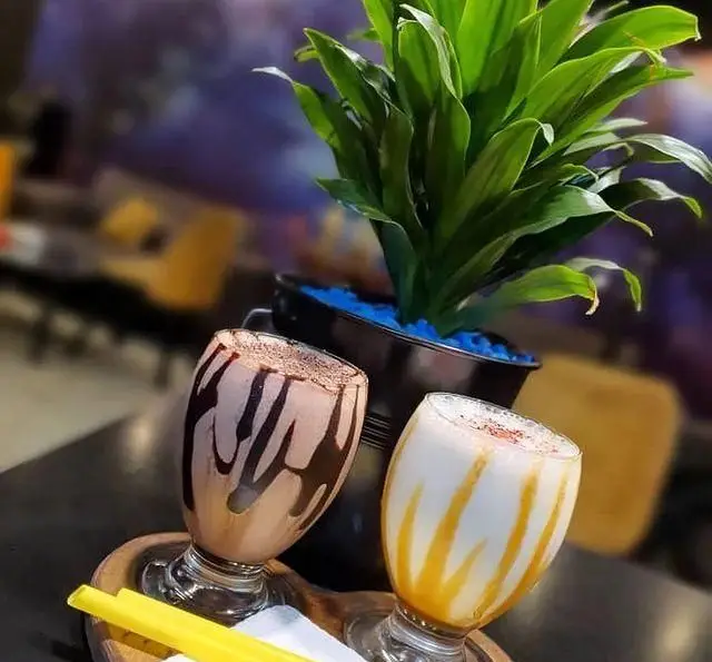 دو میلک شیک جذاب (شکلاتی و کاراملی) در کافه و سفره خانه تیام؛ لذت نوشیدنی‌های خنک و دسرهای خوشمزه در فضایی دلنشین.