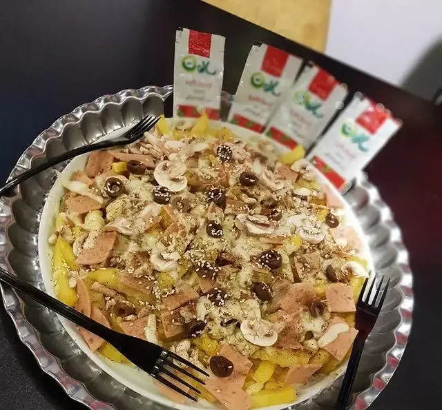 عکس نزدیک از بشقاب پرسی سیب زمینی سرخ کرده ویژه کافه و سفره خانه تیام با قارچ، زیتون، ژامبون و سس پنیر؛ یک غذای فوق العاده خوشمزه.