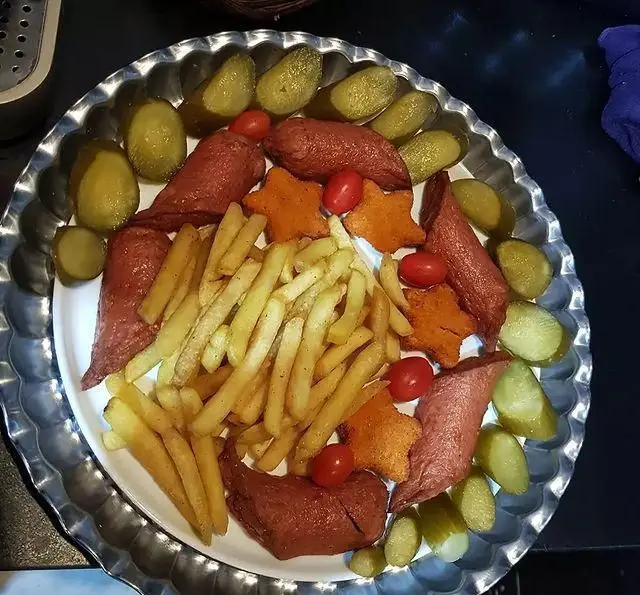 سینی غذای کافه و سفره خانه تیام: سیب‌زمینی سرخ کرده، سوسیس، خیارشور و گوجه گیلاسی. یک فست فود خوشمزه و پرطرفدار.