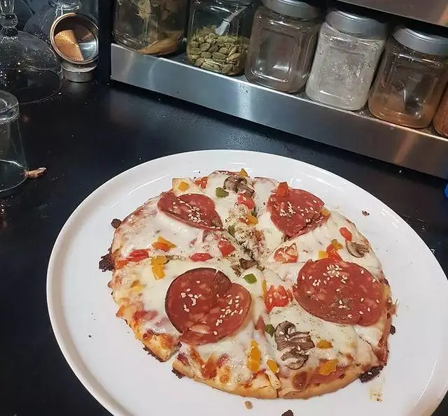 پیتزا پپرونی و قارچ خوشمزه کافه و سفره خانه تیام با پنیر فراوان، فلفل دلمه و کنجد، مناسب برای ناهار یا شام.