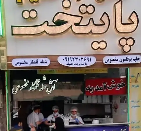 آش و حلیم پایتخت، تابلوی مغازه با ذکر شله قلمکار و حلیم بوقلمون مخصوص. نمایی از کسب و کار غذای سنتی با پرسنل آماده خدمت.