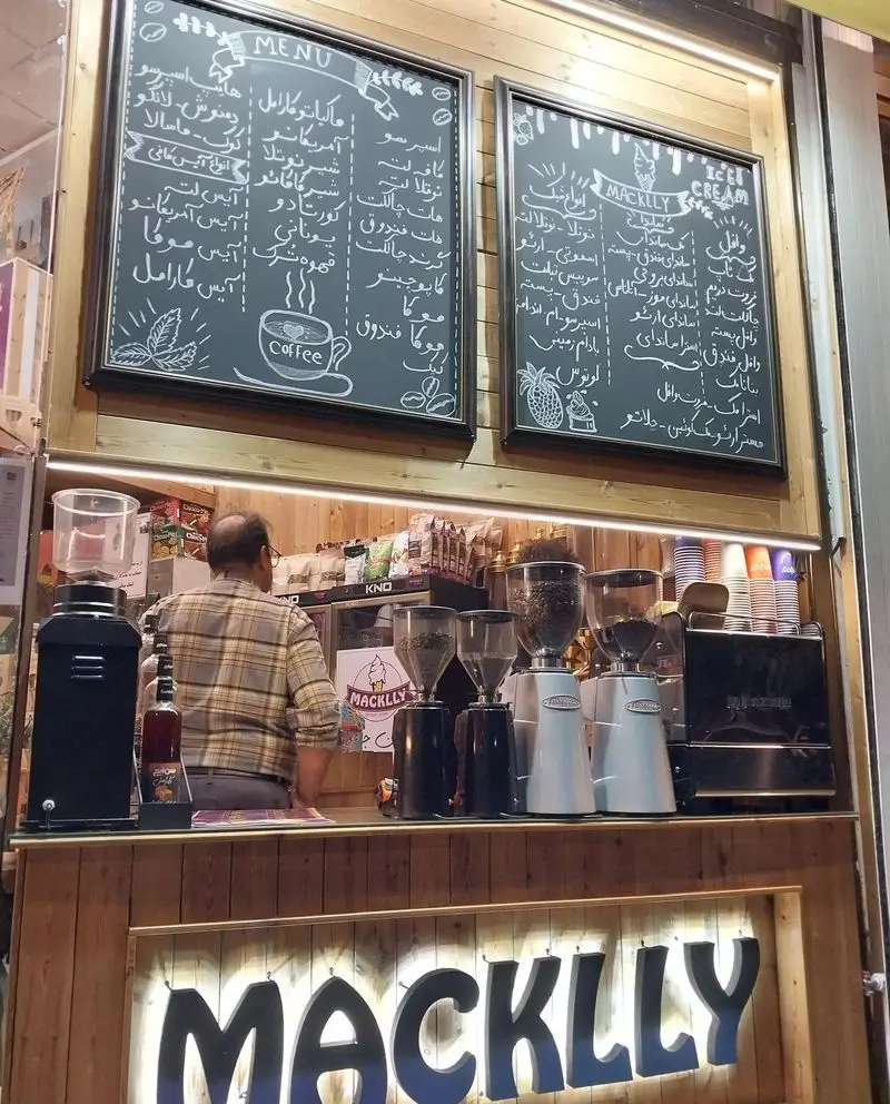 فضای داخلی کافه بستنی مکلی نیروهوایی: منو جامع قهوه، اسپرسو، بستنی، دسرها روی تخته‌سیاه و تجهیزات آماده‌سازی مدرن.