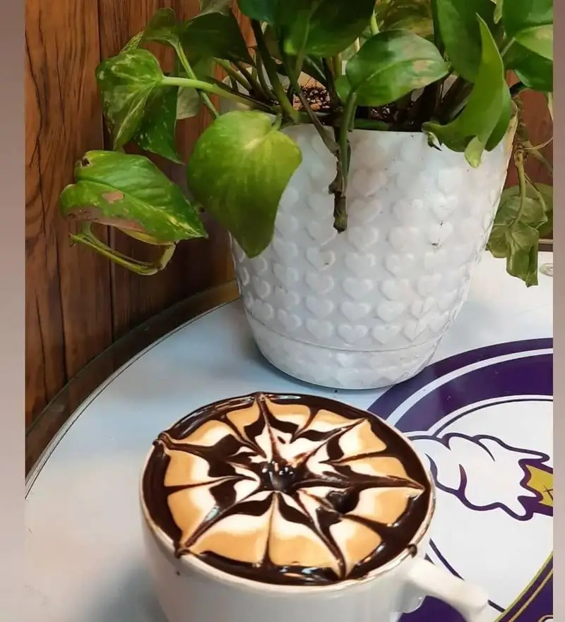 فنجان قهوه لذیذ با لاته آرت زیبا، طراحی منحصر به فرد شکلات روی فوم در بستنی مکلی نیروهوایی. لذت نوشیدنی‌های خاص.