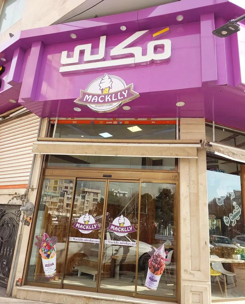 بستنی مکلی نیروهوایی: نمای جذاب فروشگاه دسر با رنگ بنفش و تابلو MACKLLY به همراه لوگوی بستنی قیفی. آماده ارائه بهترین بستنی و دسرهای تازه و خوشمزه.