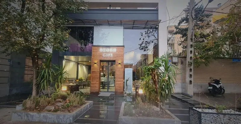 نمای بیرونی شیک کافه رستوران صدصا با طراحی مدرن، درب چوبی، پنجره‌های بزرگ و فضای سبز جلویی، محیطی دلنشین و دنج.