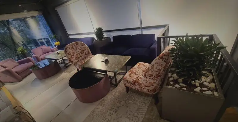 کافه رستوران صدصا: فضای داخلی دنج با مبلمان راحتی صورتی و آبی، میزهای شیک، گیاهان سبز و دکوراسیون مدرن و جذاب برای مشتریان.