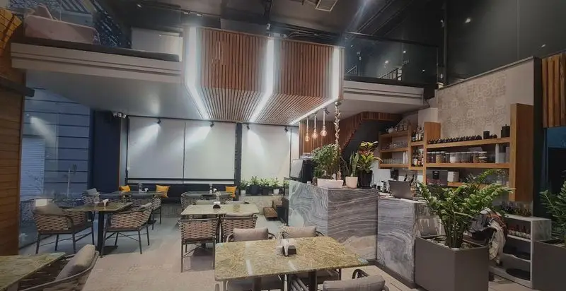 فضای داخلی کافه رستوران صدصا با دکوراسیون مدرن و شیک، شامل میز و صندلی‌های راحت، کانتر سرو، و طبقه بالا برای تجربه غذایی دلپذیر.