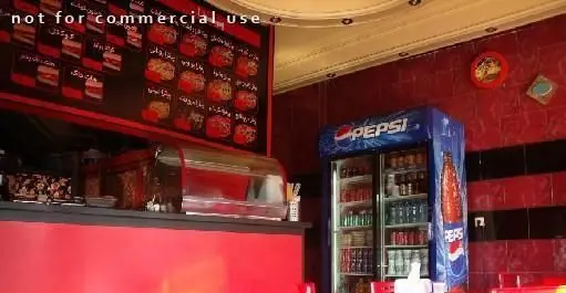 دکوراسیون داخلی مدرن فست فود هات سان با منوی متنوع غذاهای خوشمزه، یخچال پپسی و فضای شیک با دیوارهای قرمز و مشکی.