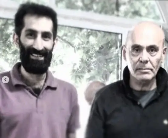 عکس دو مرد در کسب و کار عمو امید؛ مردی با ریش پرپشت و لبخند، کنار مردی مسن و طاس در محیطی روشن.