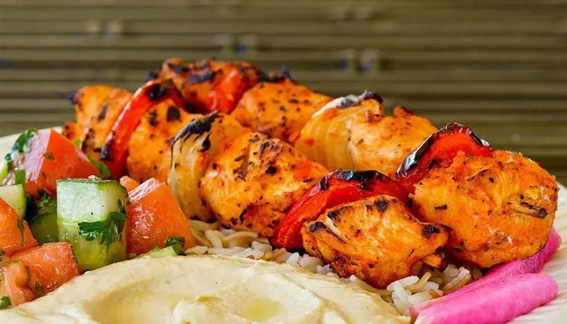 کباب لقمه سالوت: جوجه کباب شیش تاووک گریل شده با فلفل و پیاز، روی برنج، همراه حمص، سالاد تازه و ترشی. غذایی مدیترانه‌ای.