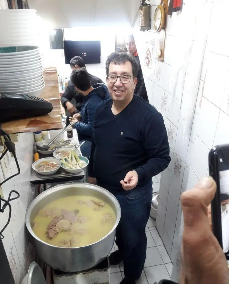 لبخند رضایت بخش منوچهر در طباخی پرطرفدار خود، طبخ کله پاچه تازه و خوشمزه در آشپزخانه شلوغ و سنتی طباخی منوچهر.