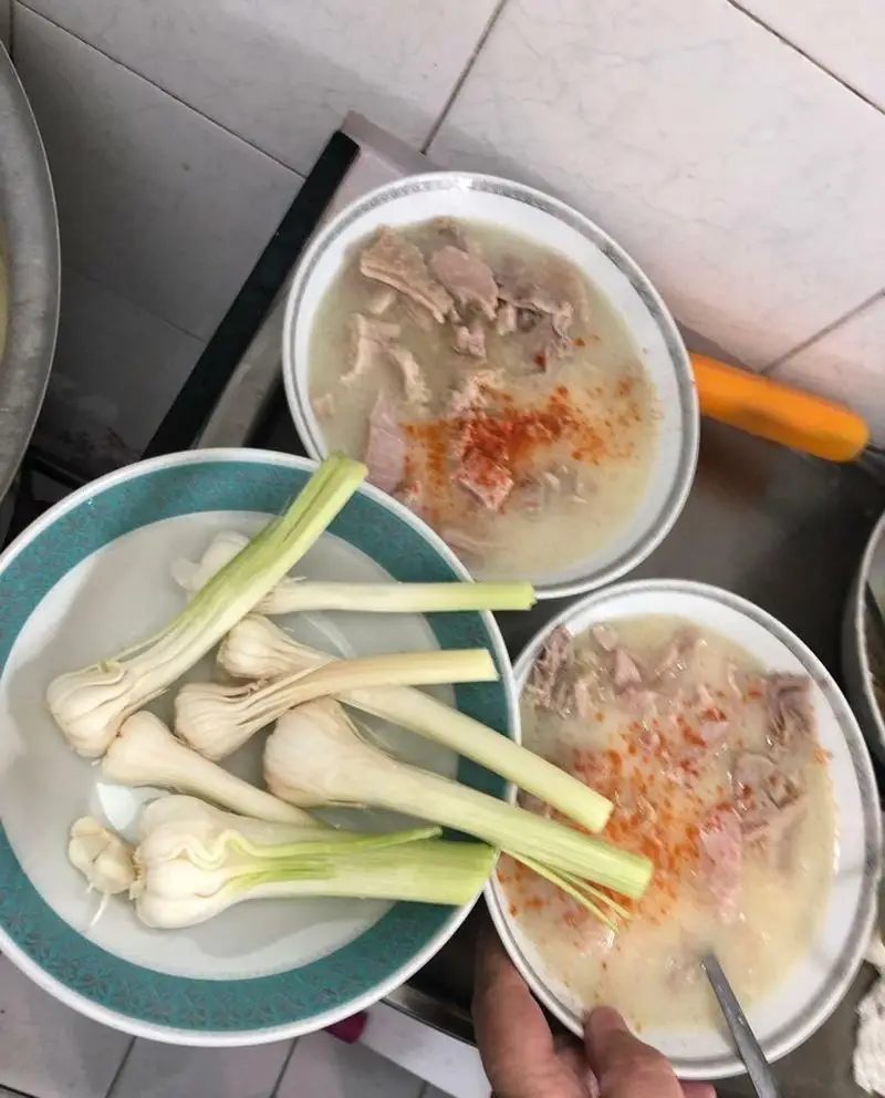 غذای داغ و سنتی طباخی منوچهر: دو کاسه سیرابی یا کله پاچه با فلفل قرمز و بشقاب سیر تازه، آماده سرو. تجربه‌ای لذیذ از غذای ایرانی.