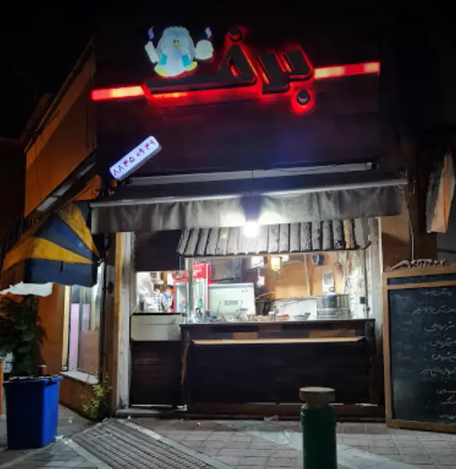 فست فود برف در شب، با تابلوی نئون چشم‌نواز قرمز، لوگوی پنگوئن شاد و پیشخوان آماده سرویس‌دهی غذای سریع و خوشمزه.