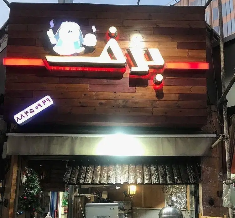 تصویر نمای بیرونی فست فود برف در شب، با تابلوی نورانی، لوگوی جذاب و شماره تماس ۸۸۴۵۰۹۴۹ برای سفارش غذای آماده و ساندویچ‌های خوشمزه.