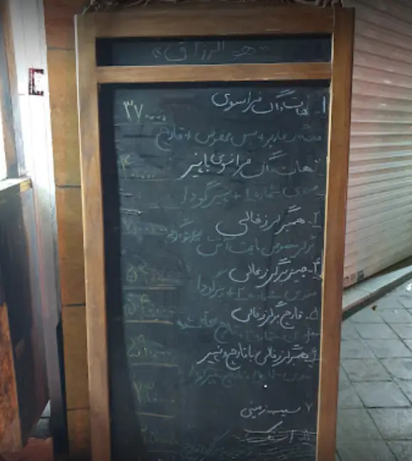 منوی فست فود برف با عنوان "هو الرزاق" روی تخته گچی چوبی، شامل همبرگر و ساندویچ‌های متنوع با قیمت.