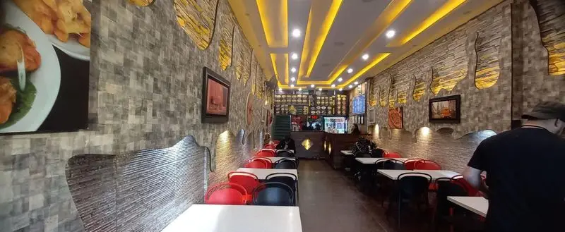 نمای داخلی فست فود دومینو با دیوارهای آجری، میز و صندلی‌های مدرن قرمز و مشکی، نورپردازی زرد و دکوراسیون منحصربه‌فرد.