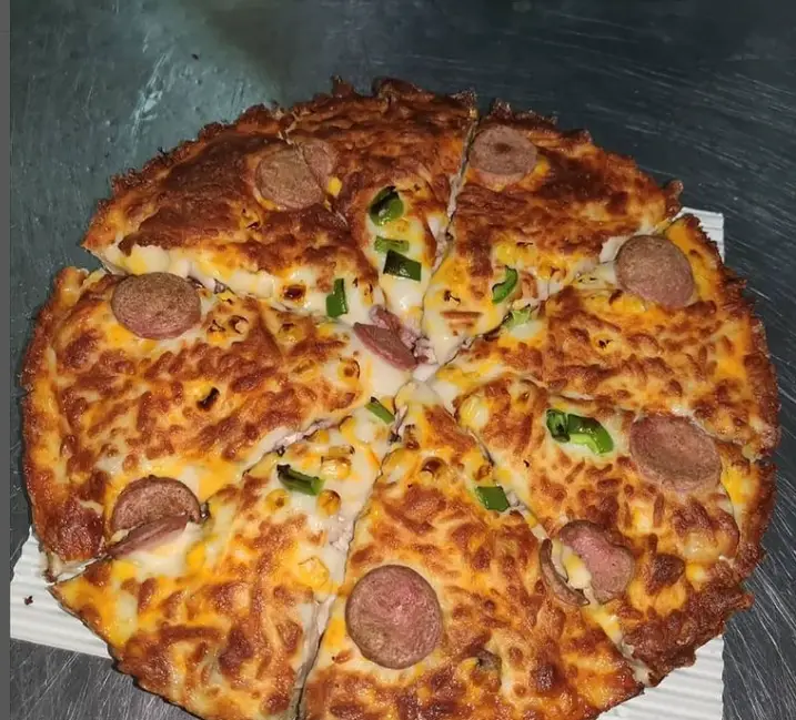 پیتزا پرملات و داغ سبحانی، برش خورده، با سوسیس، فلفل دلمه‌ای، ذرت و پنیر طلایی. آماده سفارش در پیتزا و ساندویچ سبحانی.