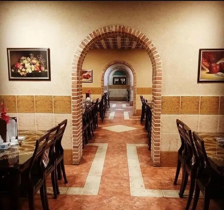 دکوراسیون داخلی رستوران سنتی سپیدار، شامل راهروهای طاق‌دار آجری، میز و صندلی‌های چوبی و نقاشی‌های سنتی روی دیوار.