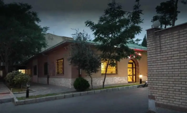 نمای شبانه رستوران سنتی سپیدار با طراحی سنتی و دلپذیر، ورودی نورانی، پنجره‌های مشبک و درختان، محیطی دعوت‌کننده برای تجربه غذا.