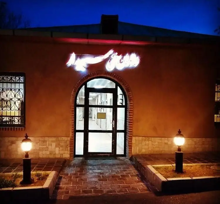 نمای شبانه ورودی رستوران سنتی سپیدار با نورپردازی گرم، تابلوی روشن و فضای دلنشین، مکانی عالی برای غذاهای ایرانی.