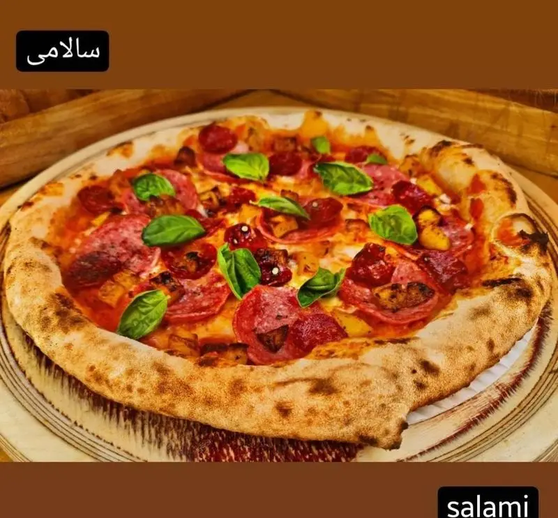 تصویری از پیتزا سالامی لذیذ و داغ کوچینا پیتزا با خمیر دست‌ساز ترد، پنیر کش‌دار فراوان و برگ‌های تازه ریحان؛ تجربه‌ای بی‌نظیر برای دوستداران پیتزا.