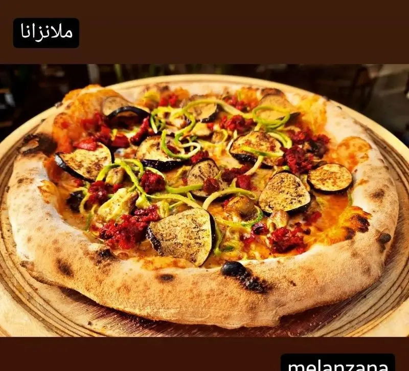 پیتزا ملانزانا مخصوص کوچینا پیتزا با بادمجان برشته، تکه‌های گوجه فرنگی خشک و رشته‌های سبزیجات تازه. یک غذای لذیذ ایتالیایی.