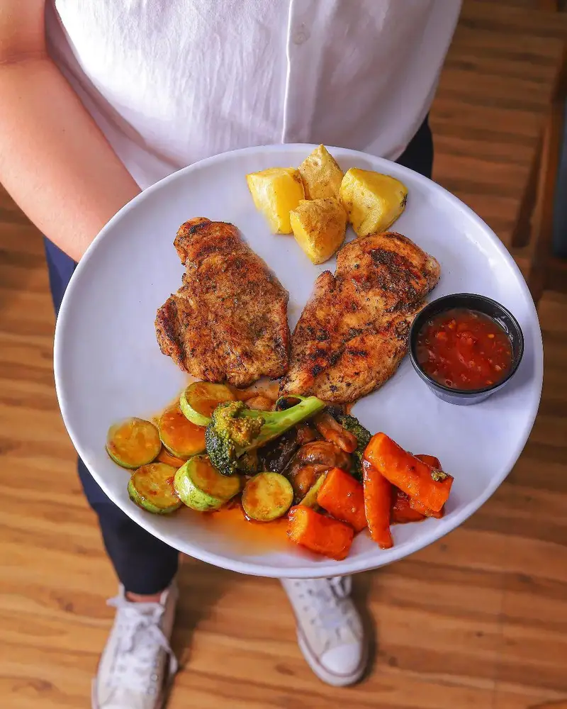 یک بشقاب غذای سالم و رژیمی کافه بینج: مرغ گریل، سبزیجات تازه (هویج، کدو، بروکلی) و آناناس. انتخابی عالی برای ناهار یا شام.