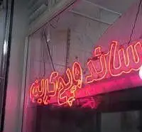 تابلوی نئون صورتی رنگ و درخشان "ساندویچ کریم" در یک مغازه ساندویچی. این تابلوی روشن و چشم نواز هویت بصری کسب و کار را نشان می‌دهد.