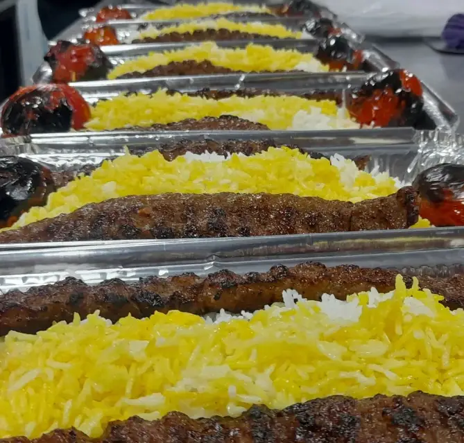 تصویری دلنشین از کباب کوبیده لذیذ با برنج زعفرانی خوش‌عطر و گوجه کبابی، تهیه شده در رستوران غذای خونگی فود شادان، مناسب سفارشات مجالس و دورهمی‌ها.