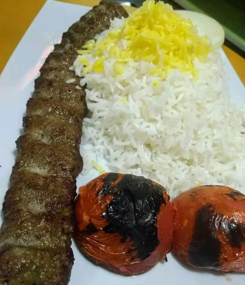 سینی چلو کباب کوبیده خوشمزه شامل کباب کوبیده، برنج سفید و زعفرانی، گوجه کبابی و پیاز. غذای خونگی فود شادان.