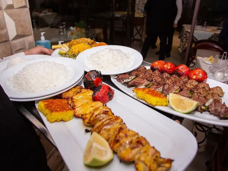 نمایی از ضیافت غذای ایرانی شامل چلوکباب کوبیده و جوجه کباب با ته چین و برنج در محیط دلنشین رستوران نایب وزرا