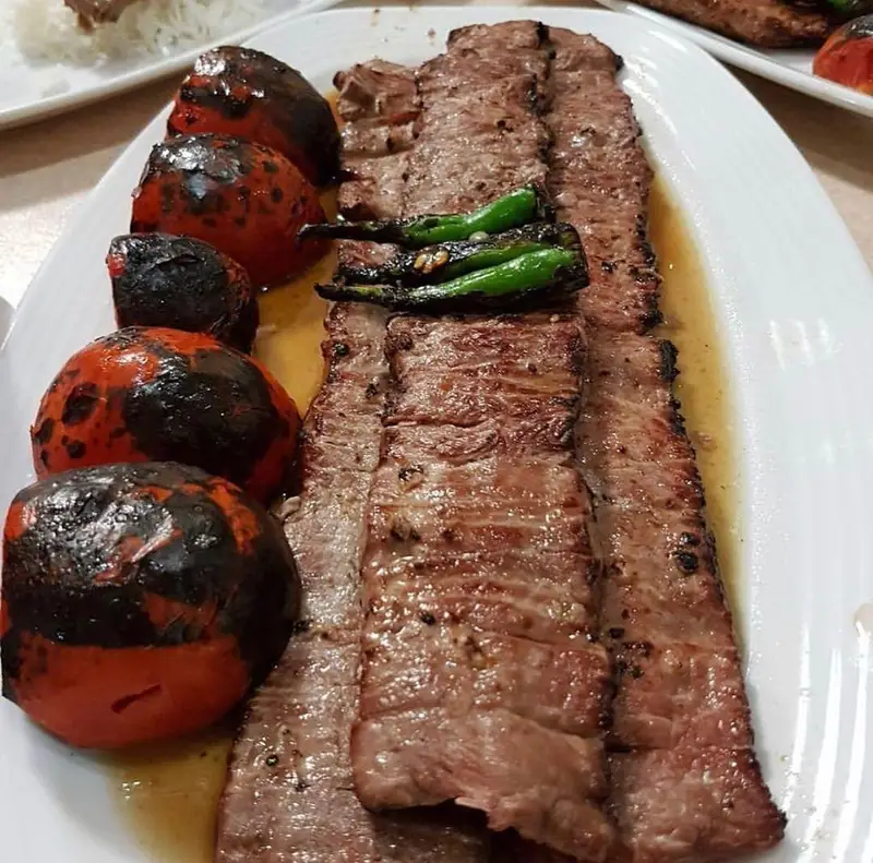 تصویری از یک پرس کباب برگ مخصوص رستوران نایب وزرا، شامل برش‌های گوشت لذیذ به همراه گوجه‌های کبابی و فلفل سبز، آماده سرو.