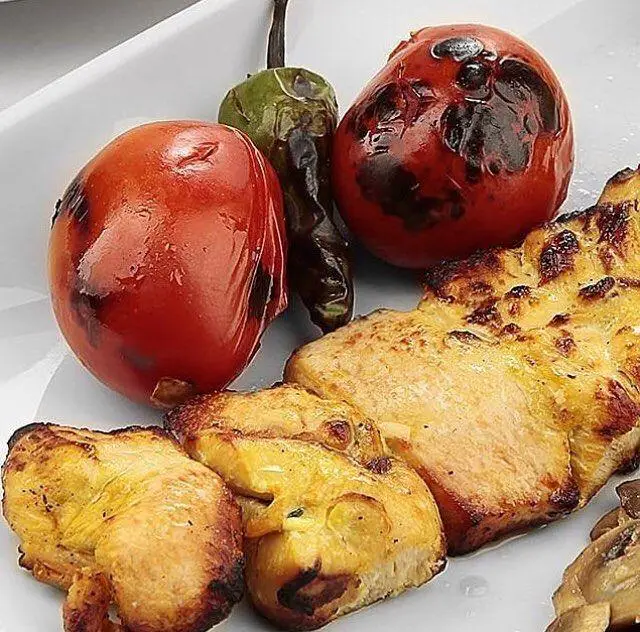 نمایی نزدیک از جوجه کباب لذیذ و خوش‌رنگ رستوران نایب وزرا، با گوجه و فلفل کبابی. بهترین غذای ایرانی برای تجربه‌ای بی‌نظیر.