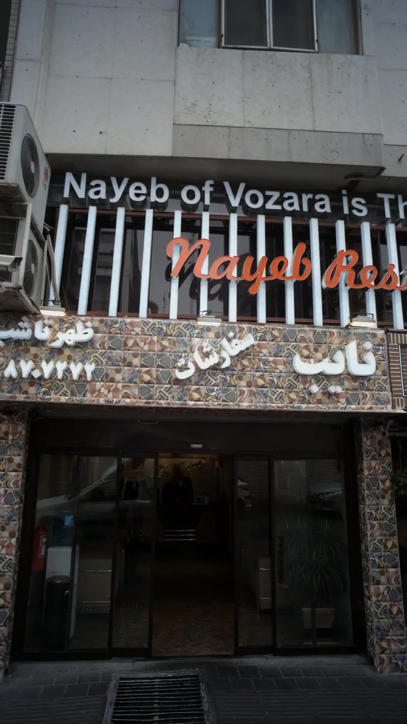 نمایی نزدیک از سردر و ورودی رستوران نایب وزرا، ارائه‌دهنده بهترین غذاهای ایرانی در تهران، آماده برای پذیرایی و ثبت سفارش.