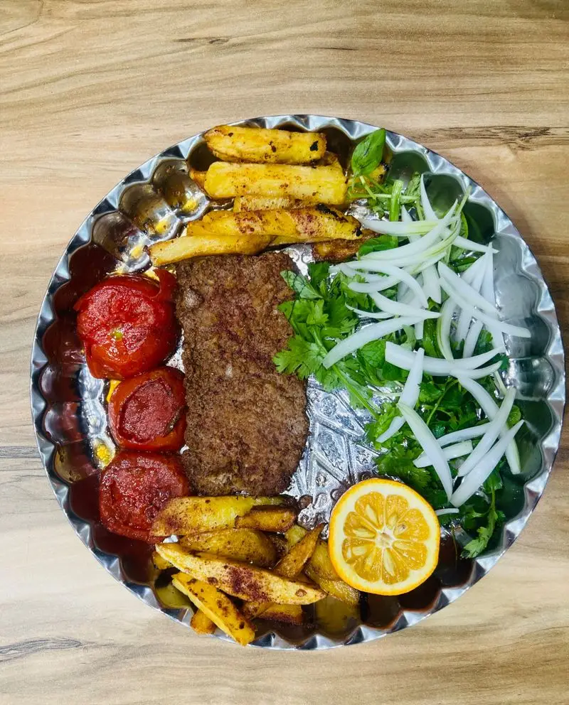 وعده لذیذ رستوران دایی دیزی: کباب ایرانی با سیب زمینی سرخ کرده، گوجه کبابی، پیاز، سبزی تازه و برش لیمو.