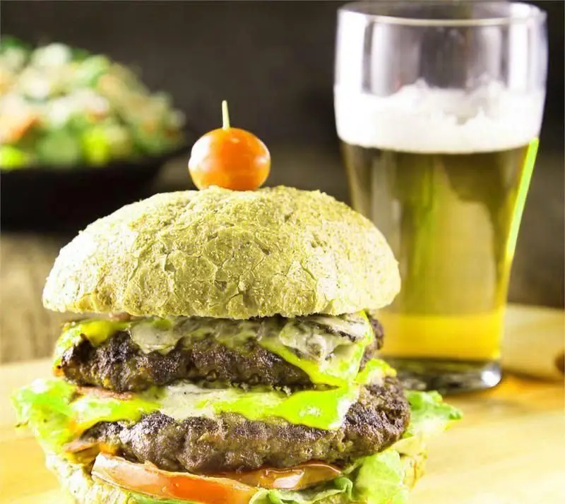 یک همبرگر دوبل جذاب با نان سبز منحصر به فرد، گوجه گیلاسی، کاهو و پنیر. همراه با لیوان نوشیدنی و سالاد. غذای عالی از بستنی ایوب.